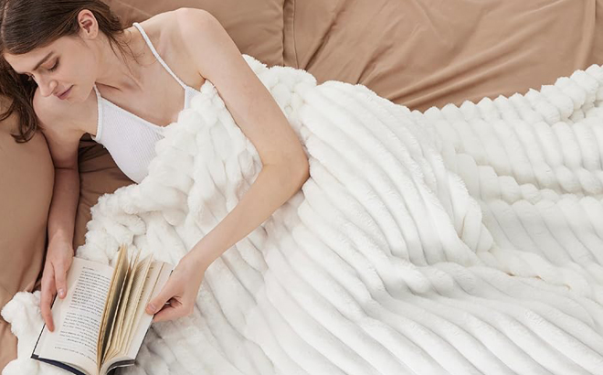 A Woman Readin on a Bed with a Bedsure White Fleece Blanket