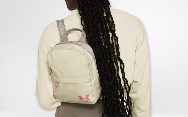 A Woman Wearing Under Armour Loudon Mini Backpack in Timberwolf Taupe