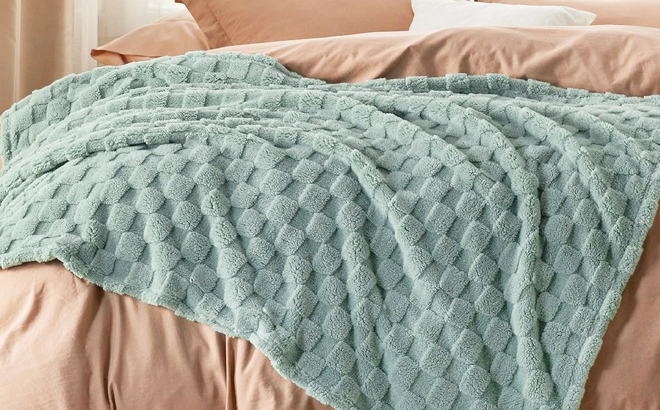 Bedsure Sage Green Fleece Blanket on a Bed