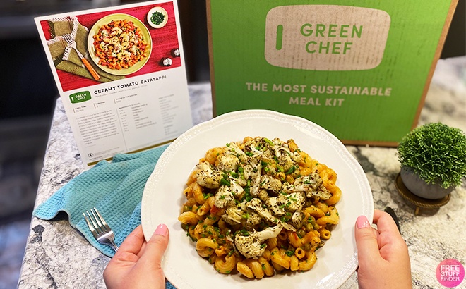 A Person Holding a Plate of Food next to a Green Chef Box