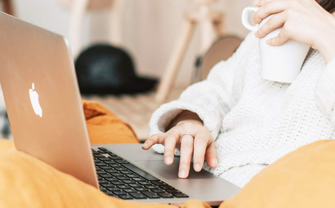 Woman Working on a Laptop and Holding a Cup of Coffee