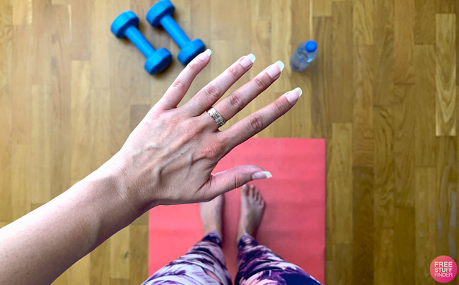 A Person Standing on a Yoga Mat showing a Ring on their Hand