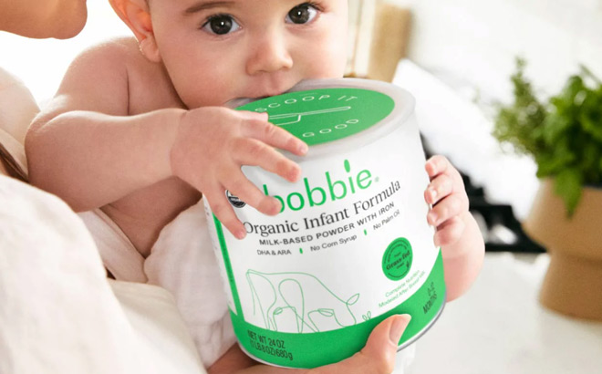 A Baby in Mothers Arms Holding a Can of Bobbie Organic Infant Formula