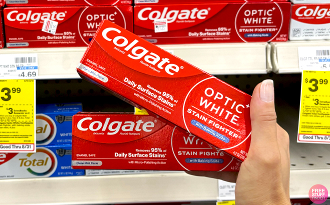 A Hand holding two Colgate Optic White Anticavity Stain Fighter Toothpastes