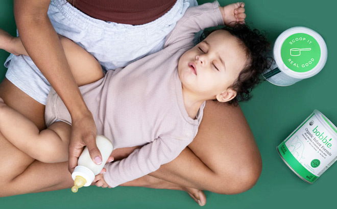 A Mother Holding a Baby Bottle in One Hand and a Sleeping Baby in Her Lap