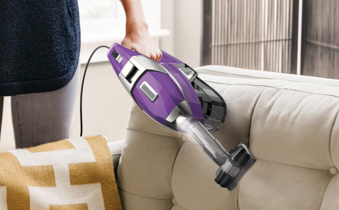 A Person Cleaning a Couch Using Shark Rocket Pet Pro Corded Stick Vacuum