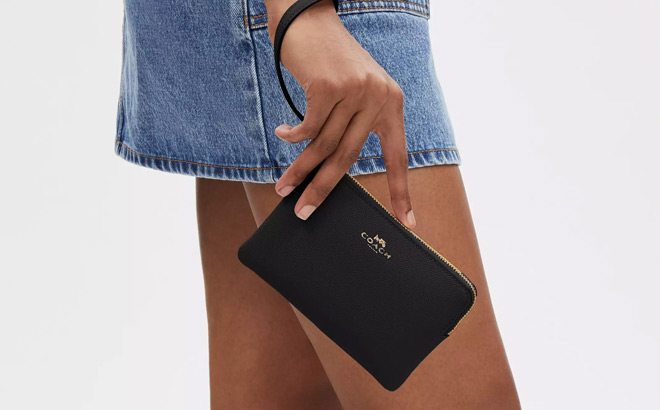 A Person Holding a Coach Outlet Corner Zip Wristlet in crossgrain leather Gold Midnight