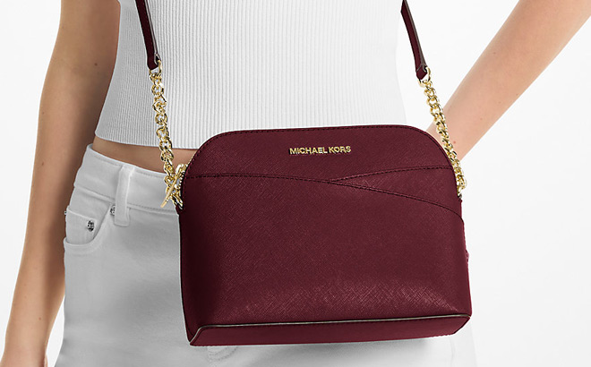 A Person Wearing Michael Kors Jet Set Travel Medium Dome Crossbody Bag in Oxblood Color