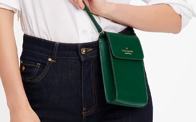 A Person Wearing the Kate Spade Outlet Madison North South Flap Phone Crossbody in Deep Jade