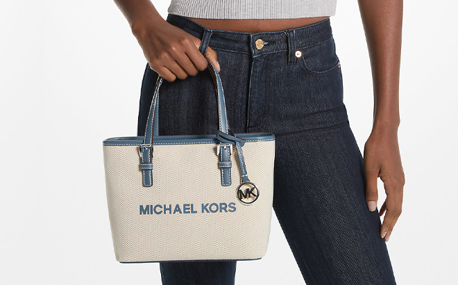 A Woman Holding Michael Kors Jet Set Travel Extra Small Canvas Top Zip Tote Bag in Denim