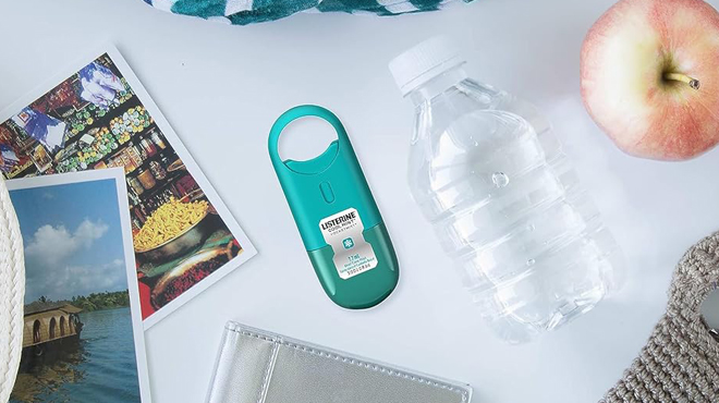 Listerine Pocketmist on a Table Beside an Apple a Water Bottle and Pictures