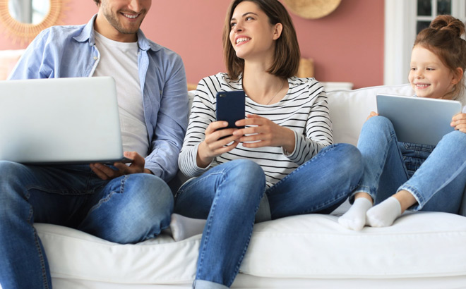 Smiling Family Using Laptop Tablet and Mobile Phone