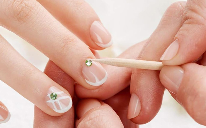 A Cuticle Stick pressing a Sticker onto a Nail