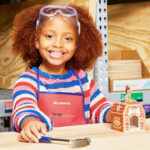 A Girl Building a Fire Dog Bank at Lowes Workshop