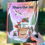 A Hand holding a Share the Joy Amazon Kids Gift Book