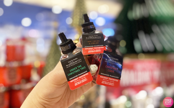 A Person Holding Three Bath Body Works Wallflower Fragrance Refills in Holiday Favorites Scents