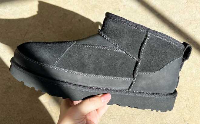 A Person Holding a UGG Womens Classic Ultra Mini ReImagined Boot in Black Color