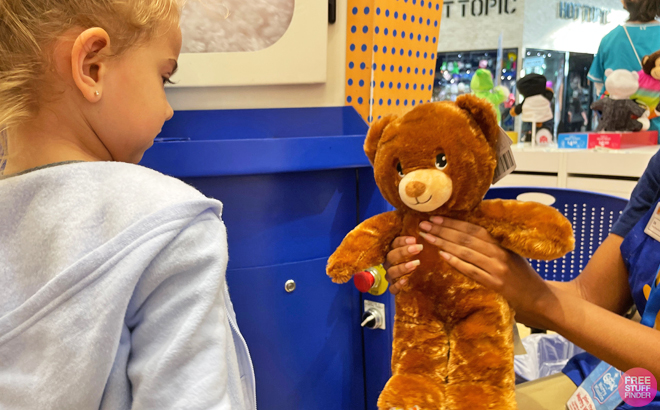 A Person Showing a Child a Build a Bear Teddy Bear