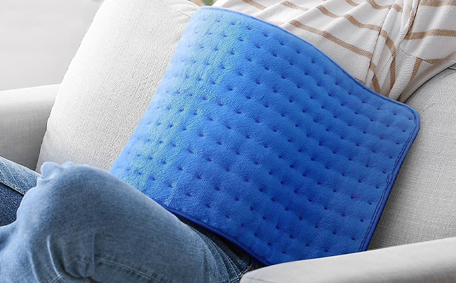 A Person Using a Heating Pad on the Couch