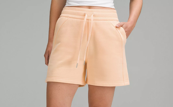 A Person Wearing Lululemon Scuba High Rise Short in Peach Bellini Color