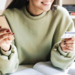 A Smiling Woman Holding Her Phone in One Hand and Credit Card in Other