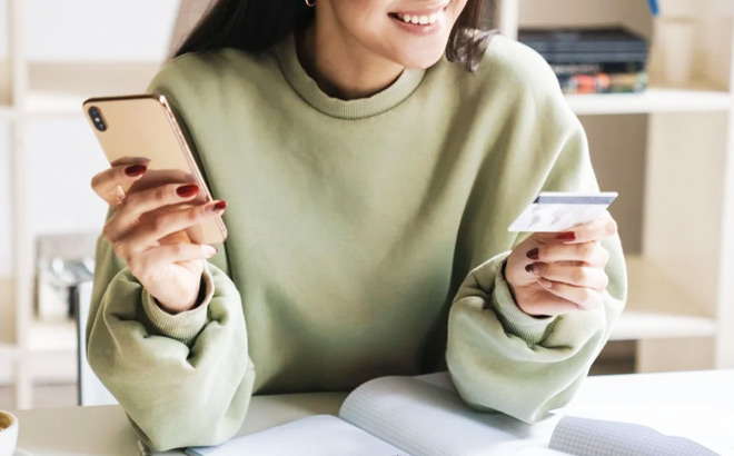 A Smiling Woman Holding Her Phone in One Hand and Credit Card in Other