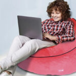 A kid seated on a Marvel Spiderman Kids Bean Bag Chair while using a laptop