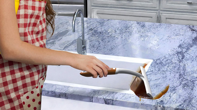 A person cleaning a kitchen counter using a Scrubit Window and Shower Squeegee