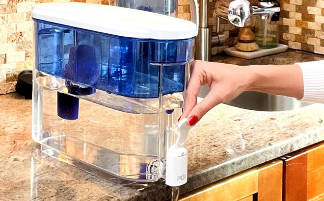 A person fetching water from a Pur 30 Cup Water Filter Dispenser