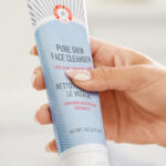 A person holding a First Aid Beauty Face Cleanser