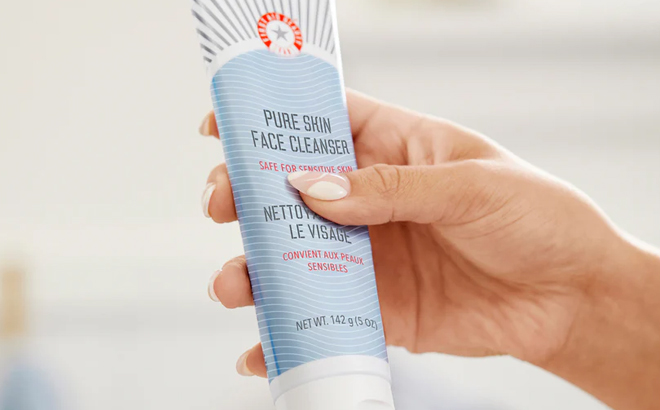 A person holding a First Aid Beauty Face Cleanser