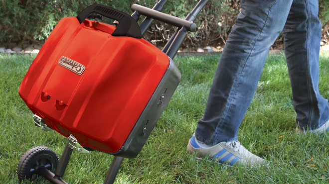 A person towing a folded Coleman Sportster Propane Grill