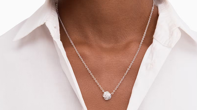 A person wearing a Kate Spade Knot Mini Pendant Necklace