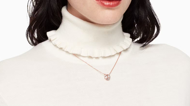 A person wearing a Kate Spade Marmalade Mini Pendant