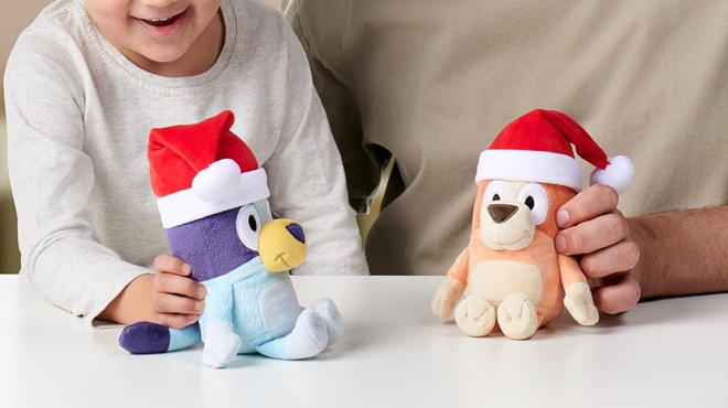 A Boy and Man Holding Bluey and Bingo Christmas Plush with Santa Hats