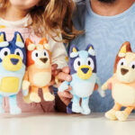 A Girl and Man Holding the Bluey Heeler Family Plush Set