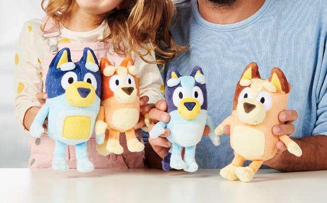 A Girl and Man Holding the Bluey Heeler Family Plush Set