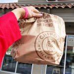 A Hand holding a Chipotle Bag