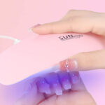 A Person Holding Mini Gel Nail Lamp in Pink Color