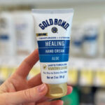 A Person Holding a Tube of Gold Bond Healing Hand Cream