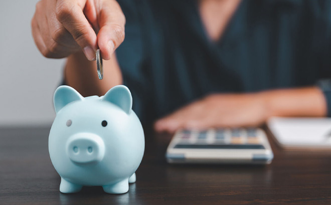 A Person Putting a Penny in a Piggy Bank