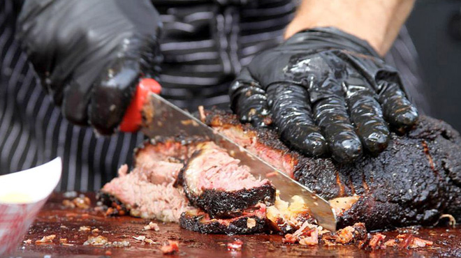 A Person Using Black Nitrile Gloves While Chopping Meat