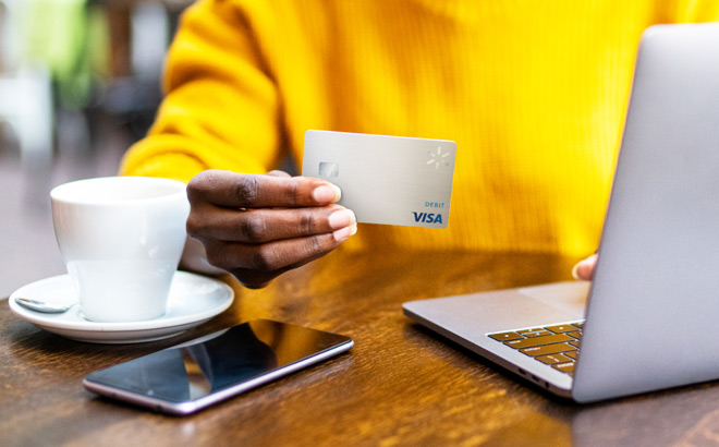 A Person Using a Laptop and Holding a Walmart MoneyCard