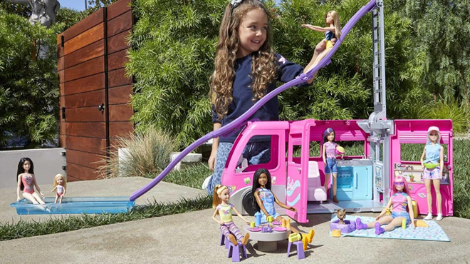 A Person playing with Barbie Camper Playset