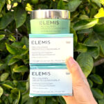 A Woman Holding Elemis Pro Collagen Green Fig Cleansing Balms