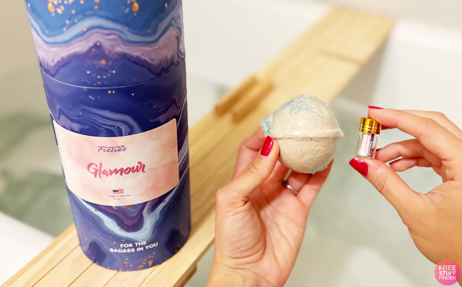 A Woman Holding a Forever Fizzies Bath Bomb and a Vial with a Diamond Inside