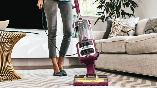 A lady cleaning a living room carpet using Shark Navigator Upright Vacuum Cleaner