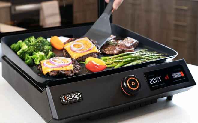 A person cooking on a Blackstone 17 inch Electric Tabletop Griddle