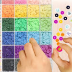 A person picking up beads from the 6 000 pc Clay Bead Bracelet Making Kit