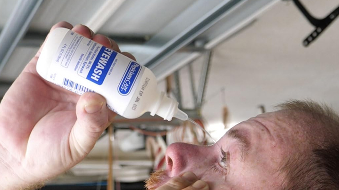 A person using a PhysiciansCare Eye Wash Solution to clean his eyes